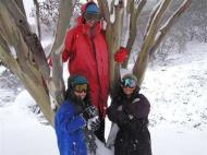 Woman and two children in front of a tree, surrounded by snow